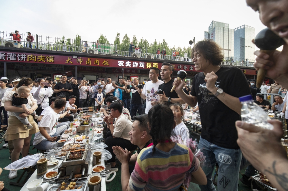 A singer performs for a table of diner at a barbecue place in Zibo, China, May 2, 2023. (Qilai Shen/The New York Times)