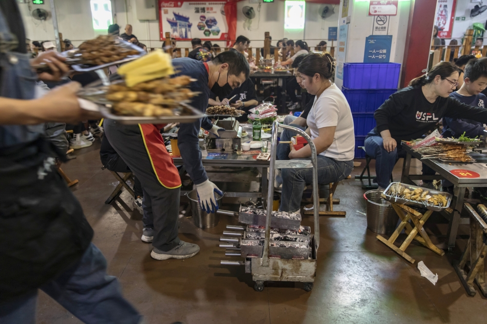 Diners and servers at a barbecue place in Zibo, China, May 2, 2023. (Qilai Shen/The New York Times)