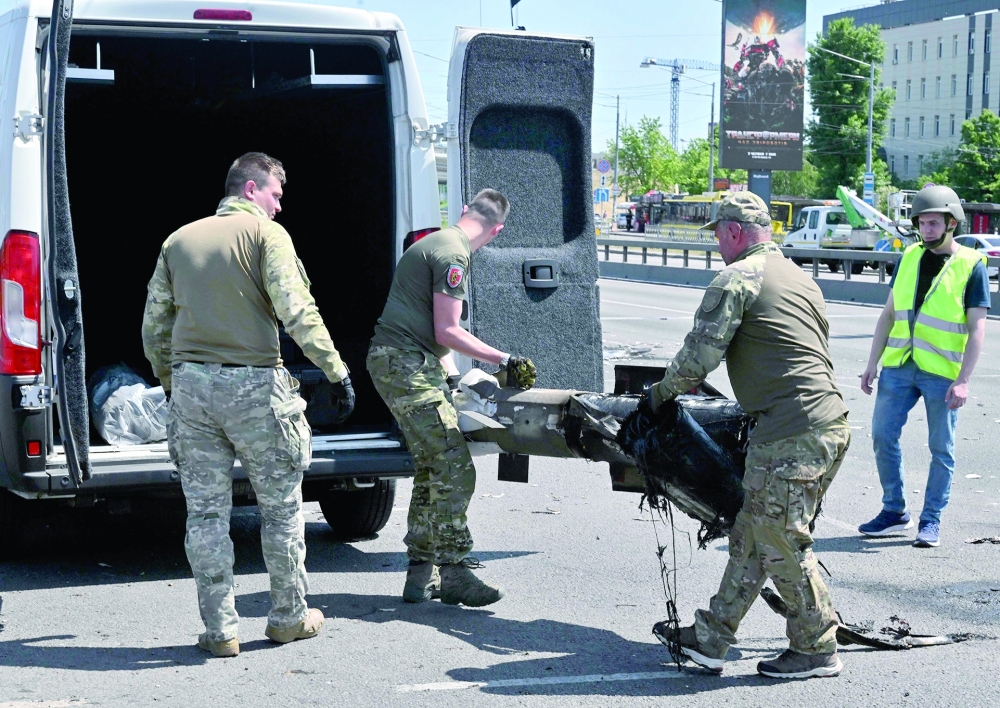 Police experts load fragments of a missile into a car after Russia fired a barrage of missiles targetting the Ukrainian capital. — AFP 