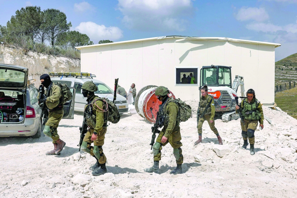 Israeli solders walk outside a portable building under construction at the former Israeli settler outpost of Homesh in the occupied West Bank. — AFP 