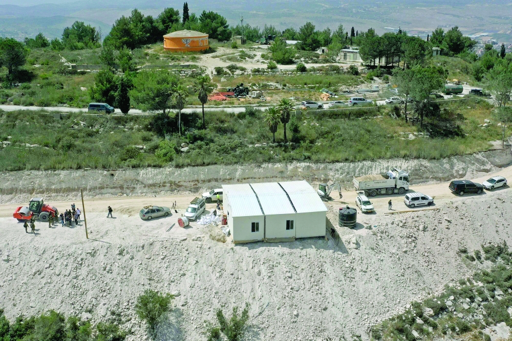 An aerial view shows people around a portable building under construction at the Israeli settler outpost of Homesh in the occupied West Bank. — AFP 