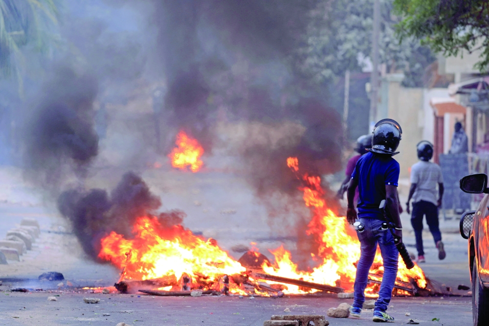 A member of security forces stands next to a burning barricade set  by supporters of opposition leader Ousmane Sonko in Dakar. — Reuters 