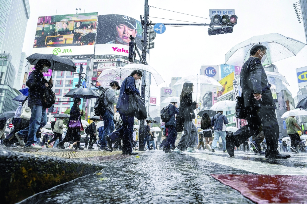 People use their umbrellas to shelter from the rain as they walk through Shibuya district in Tokyo. - AFP


