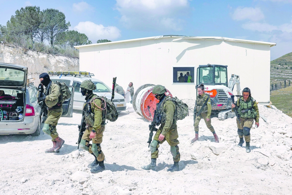 Israeli solders walk outside a portable building under construction at the former Israeli settler outpost of Homesh in the occupied West Bank. — AFP