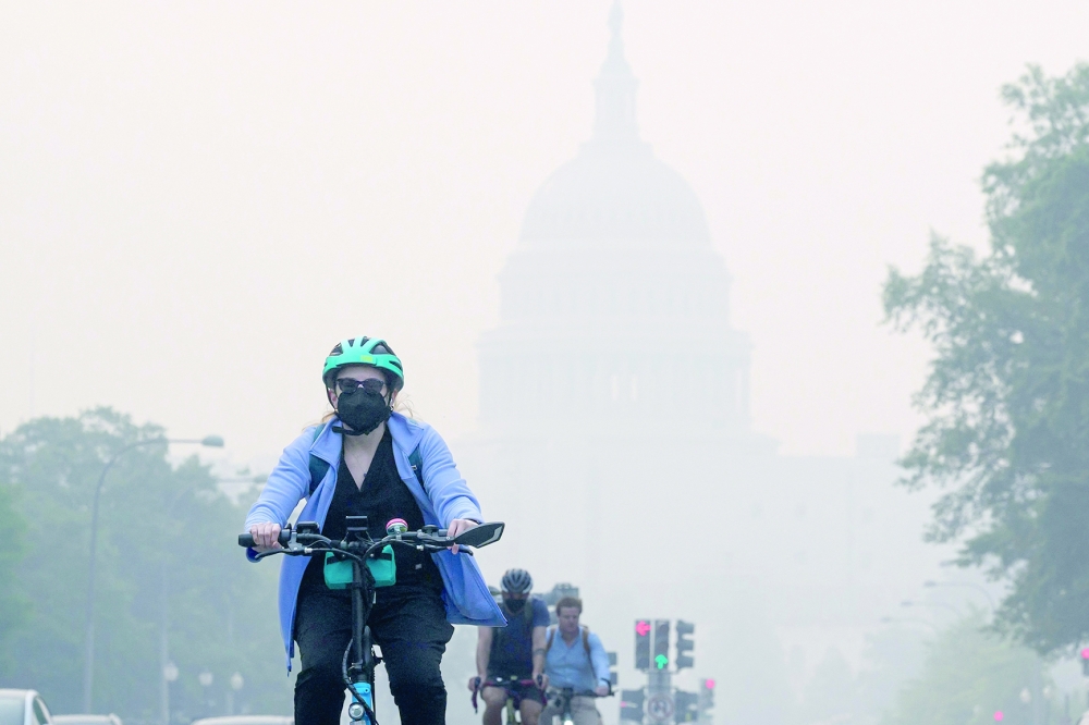 A cyclist rides under a blanket of haze partially obscuring the US Capitol in Washington, DC. - AFP 