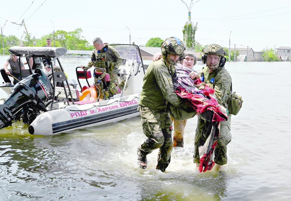 Ukrainian servicemen help to unload a disabled local resident from a boat during an evacuation from a flooded area in Kherson. - AFP
