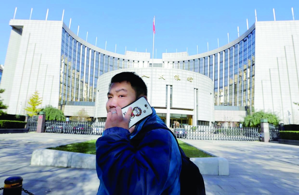 A man on a phone walks past the People's Bank of China in Beijing. — Reuters