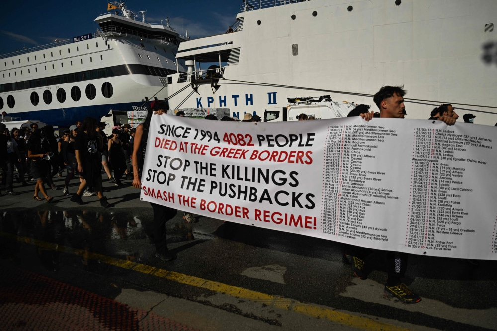 Protesters carry a banner listing the cases of migrants' deaths during a protest march to Frontex and Hellenic Coastguard headquarters in the port of Piraeus. — AFP