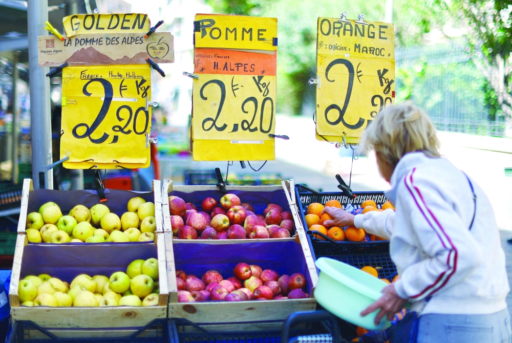 Price tags are seen on fruits as a woman shops at a local market in Nice, France. — Reuters