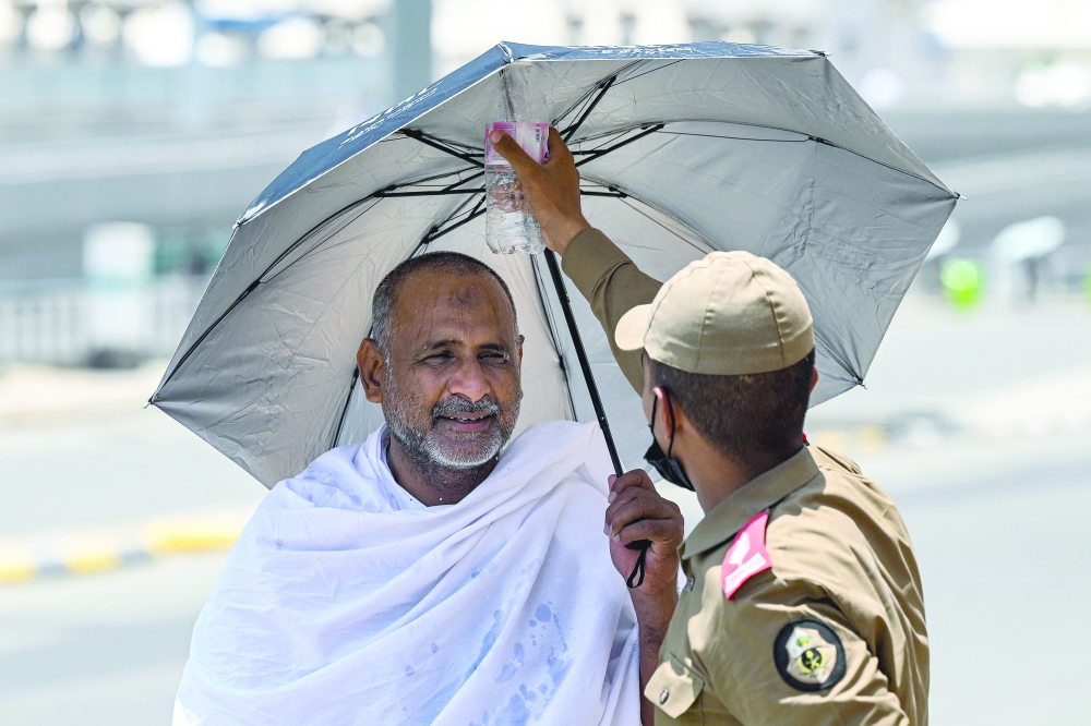 A member of security sprays water on a Muslim pilgrim upon his arrival in Mina. — AFP 