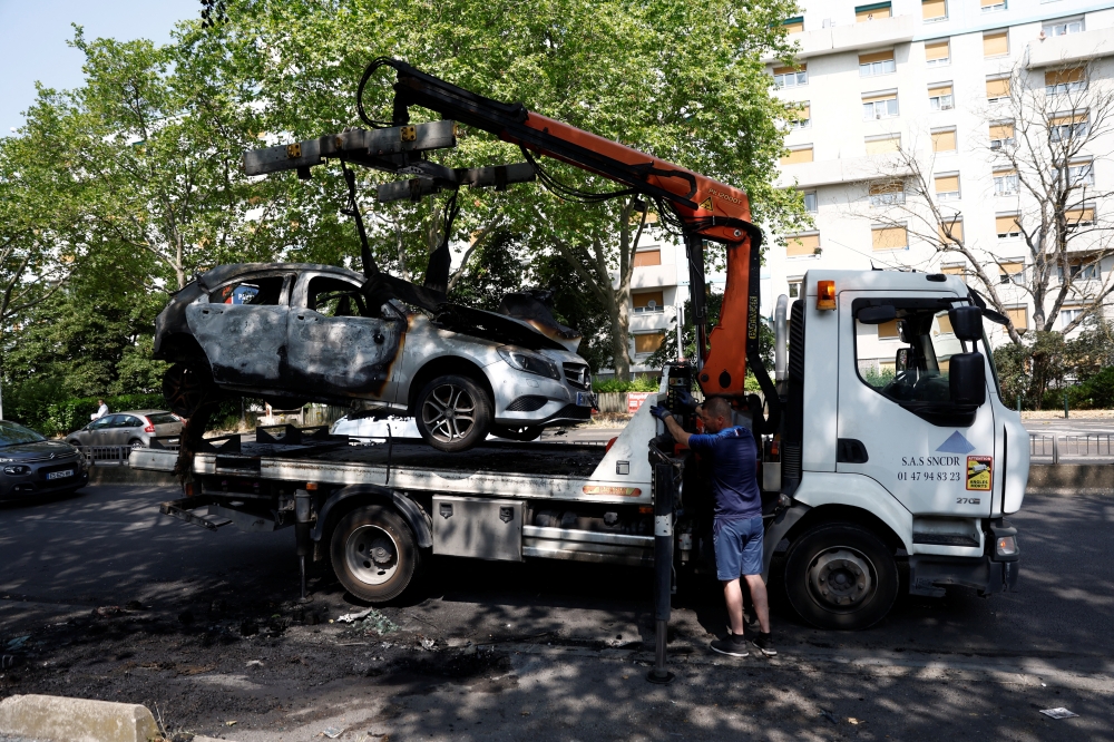 A burnt car is removed from the street the day after the death of a 17-year-old teenager killed by a French police officer during a traffic stop, in Nanterre, Paris suburb. — Reuters