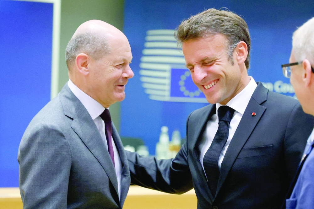 Germany's Chancellor Olaf Scholz shares a light moment with French President Emmanuel Macron as they attend the European Council Summit, at the EU headquarters in Brussels. - AFP