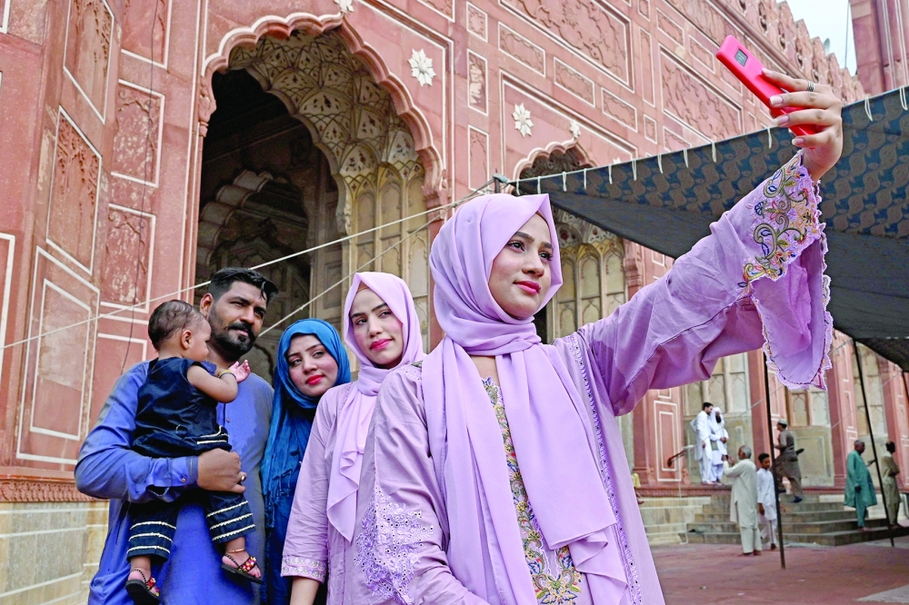Devotees take pictures after offering prayers at the Badshahi mosque during Eid al Adha in Lahore. - AFP

