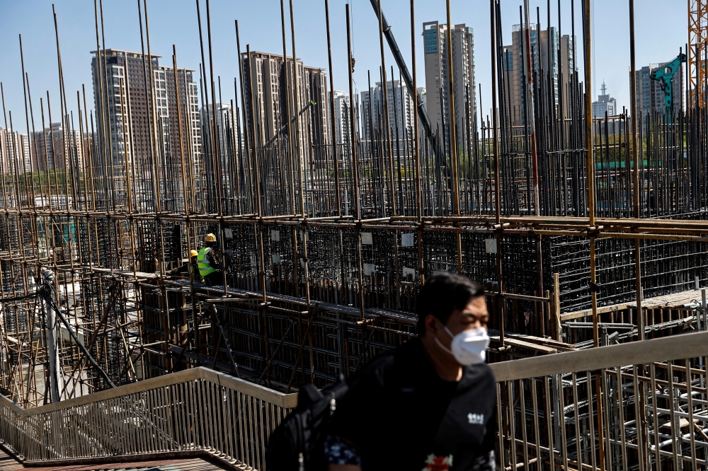 A man walks on an overpass near a construction site of a subway station in Beijing, China. — Reuters