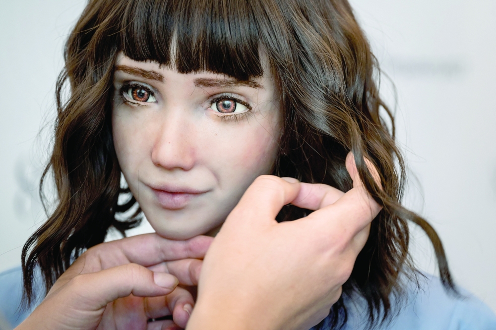 A staff sets the wig of healthcare assistant robot 'Grace' at the booth of SingularityNET company during the world's largest gathering of humanoid AI Robots as part of ITU AI for Good Global Summit in Geneva. - AFP