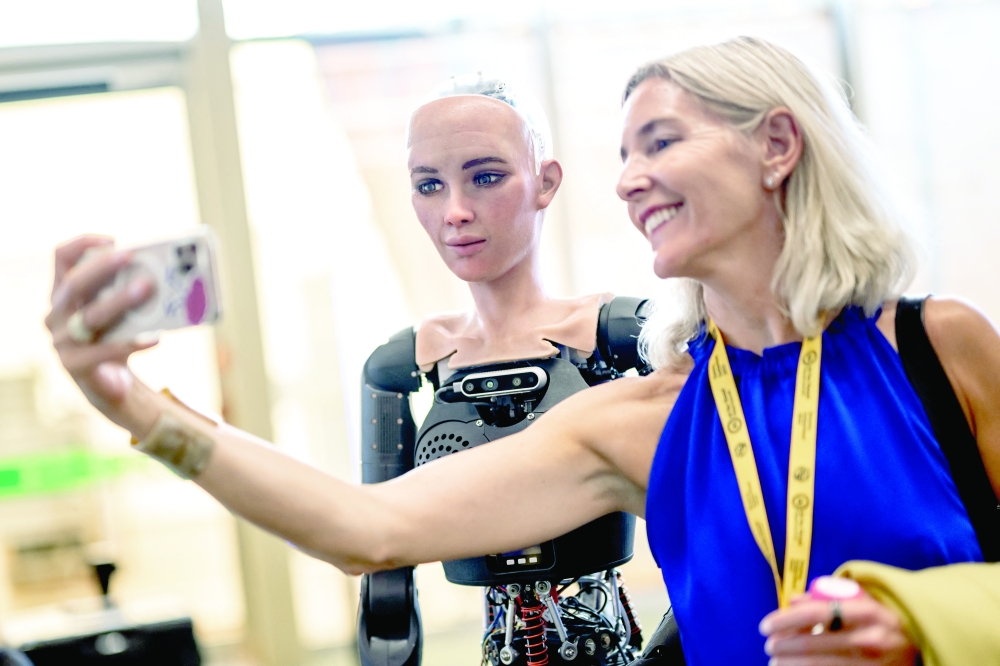 A visitor takes a selfie with 'Sophia' at the booth of Hanson Robotics during the world's largest gathering of humanoid AI Robots as part of ITU AI for Good Global Summit in Geneva. - AFP