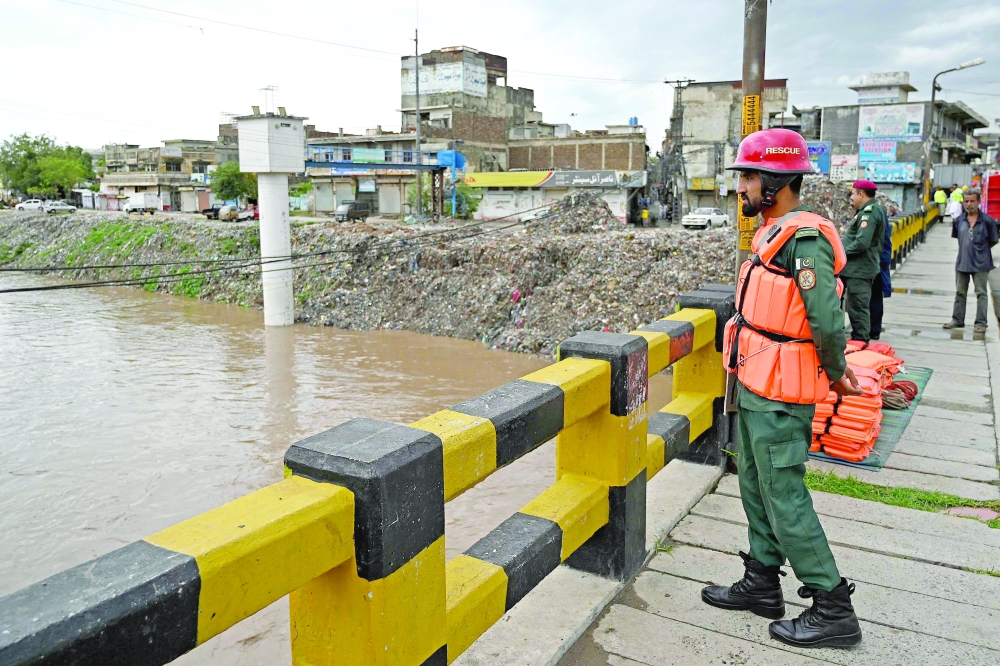 Rescue workers monitor the flood situation at a bridge over a stream in Rawalpindi. - AFP