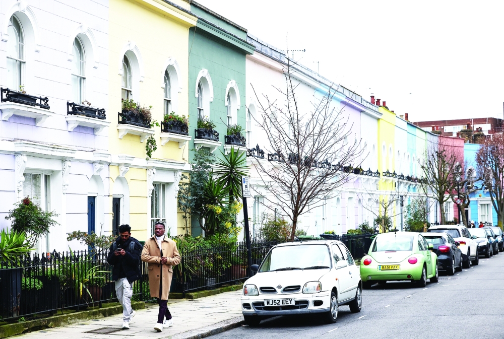 People walk past a row of colourful houses in London, Britain. — Reuters