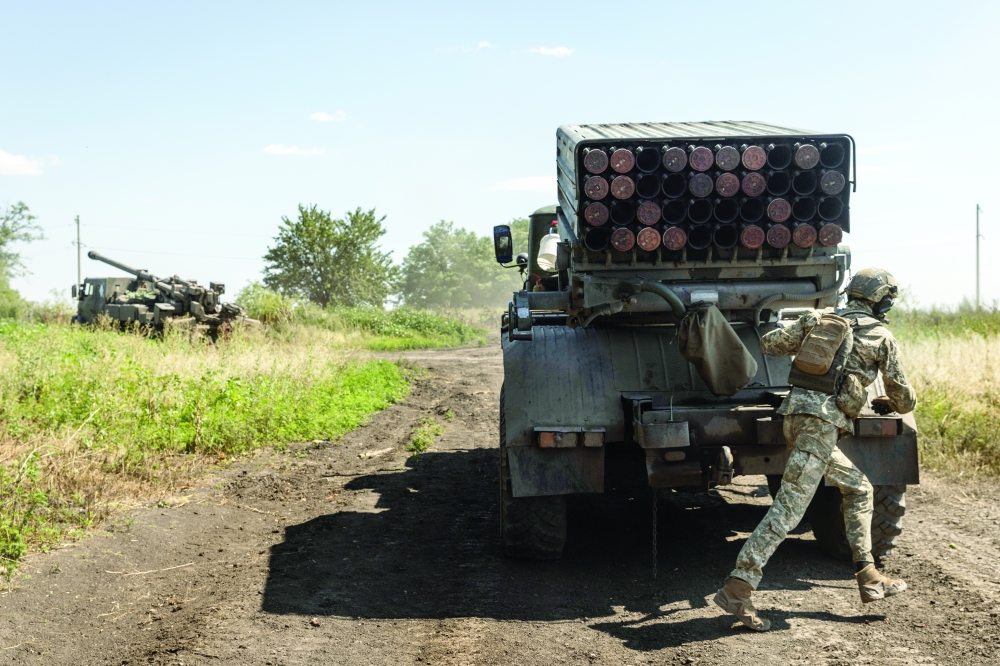 Ukrainian Marines from the 36th Brigade rush to pack up after firing rockets from a Grad launcher toward Russian infantry in a frontline tree line position as an artillery team arrives to fire nearby in the Zaporizhzhia region of Ukraine, July 13, 2023. (David Guttenfelder/The New York Times)