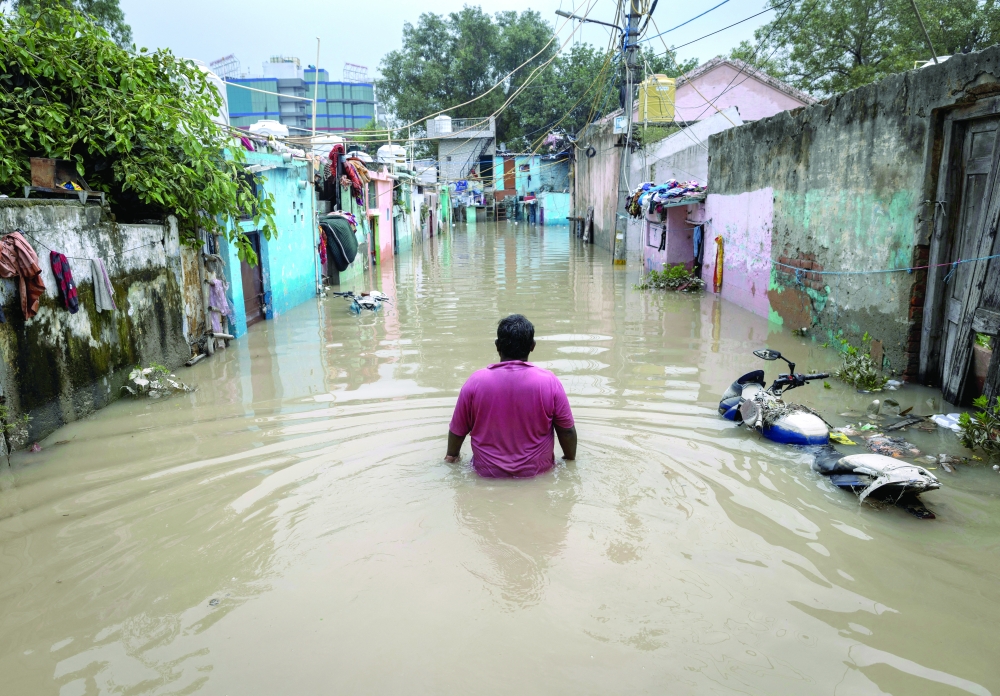 A man walks through a flooded alley at a residential colony, after water rose from the river Yamuna due to heavy monsoon rain in New Delhi. - Reuters