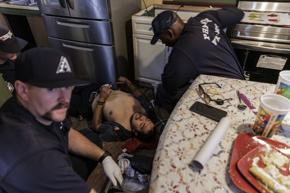Paramedics assist Alex Guerrero, who suffered heatstroke, at his family’s home in Phoenix, July 15, 2023. (Adriana Zehbrauskas/The New York Times)