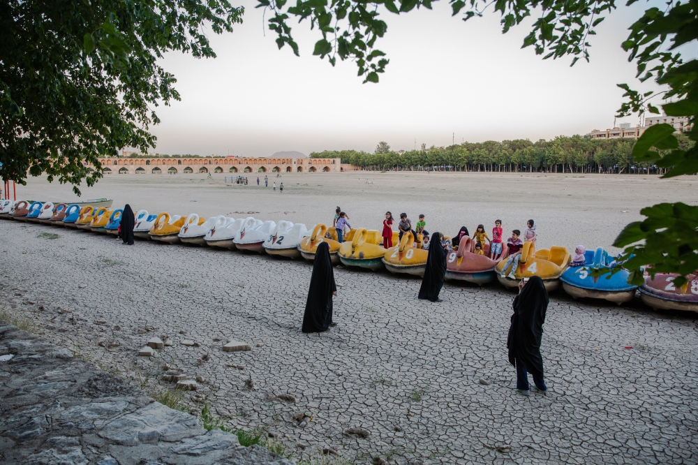 Children clamber around paddle-boats marooned alongside a dried-out riverbed in Isfahan, Iran in June 2023. (The New York Times) 