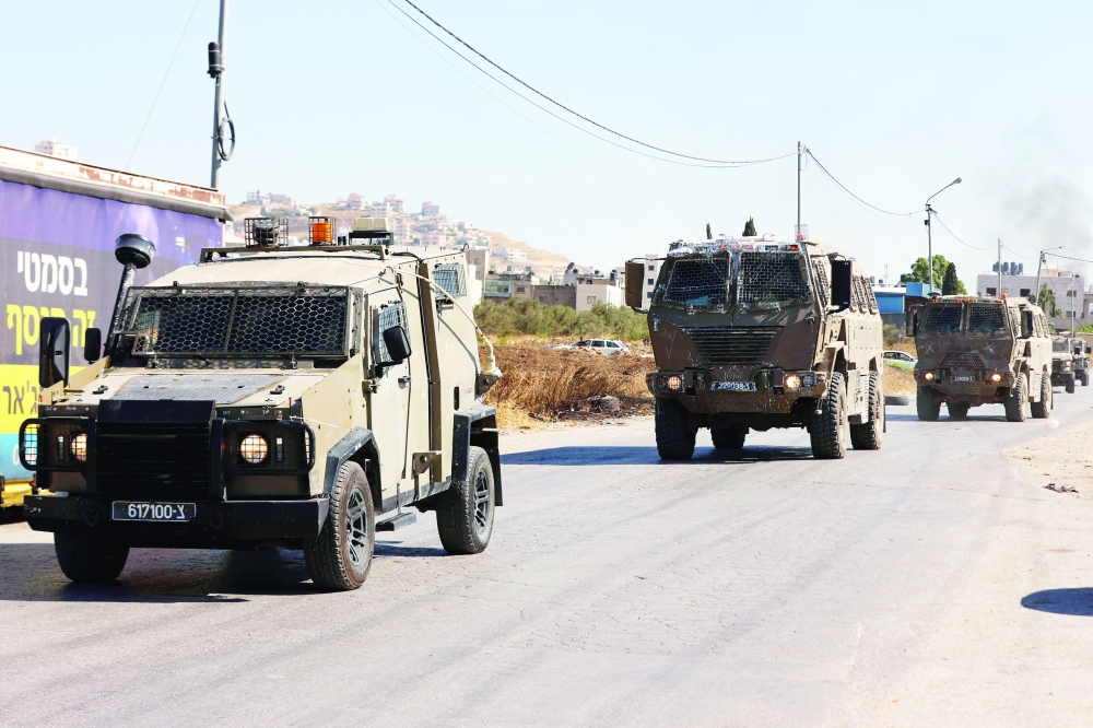 Israeli armoured vehicles advance during a military raid to search for wanted Palestinians at the Askar refugee camp east of Nablus in the occupied West Bank. — AFP