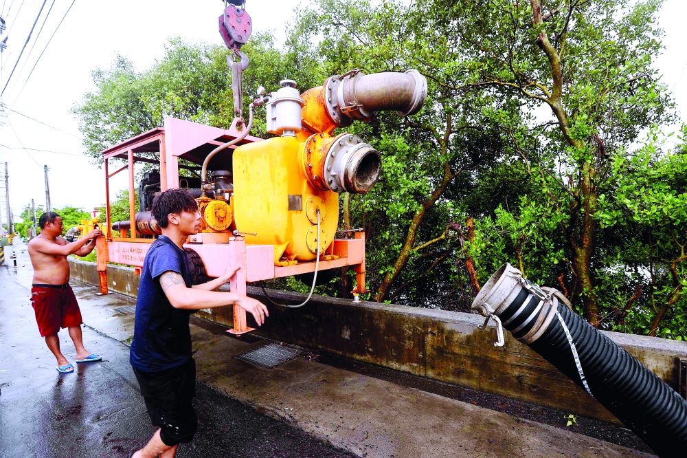 Local residents prepare a water pump in Linbian in western Pingtung County as Typhoon Doksuri past southern Taiwan. — AFP