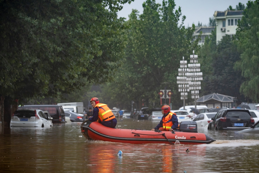 Rescue workers in a boat go through a flooded street in a neighbourhood where days of heavy rain from remnants of Typhoon Doksuri caused heavy damage in Beijing