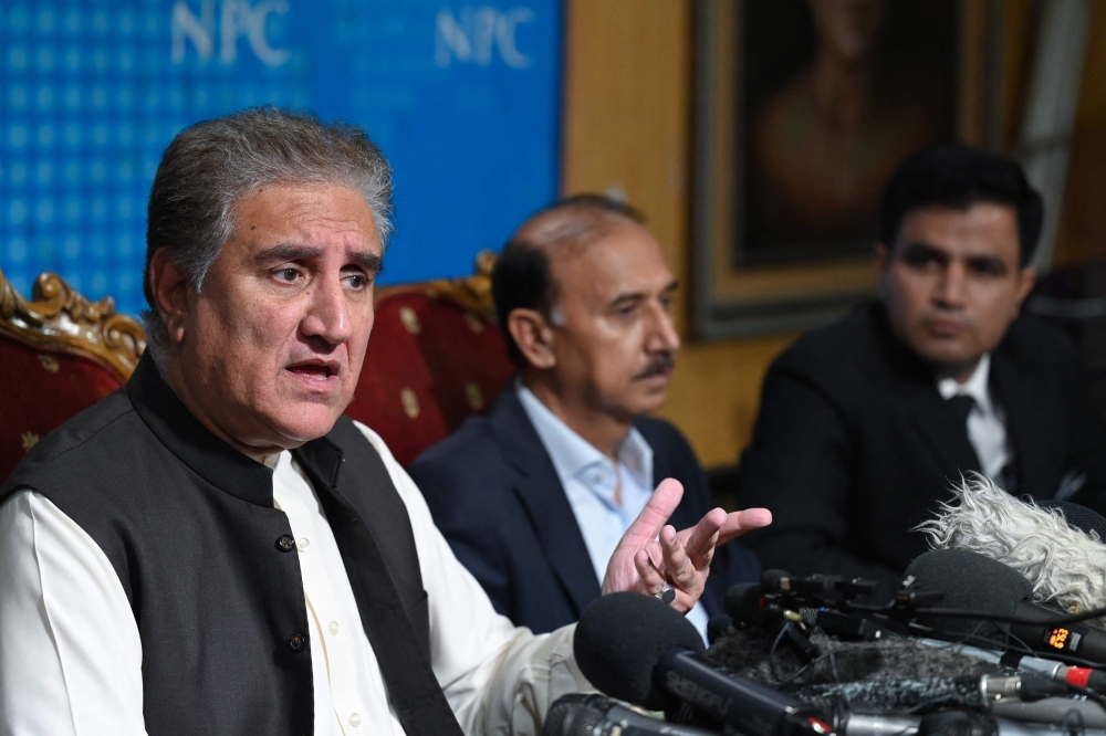 Shah Mahmood Qureshi (L), deputy head of Pakistan Tehreek-e-Insaf (PTI) party speaks as Naeem Haider Panjutha (R), spokesperson to former Pakistan's Prime Minister Imran Khan on legal affairs listens, during a media briefing in Islamabad on August 7, 2023.