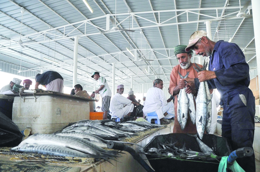 Vendors prepare the fish for display at a local market in Muscat.