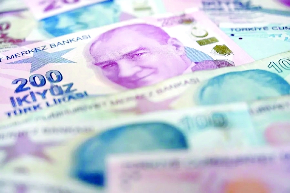 A picture taken on December 7, 2021 in Istanbul shows US dollars banknotes and Turkish lira banknotes. (Photo by Ozan KOSE / AFP)
