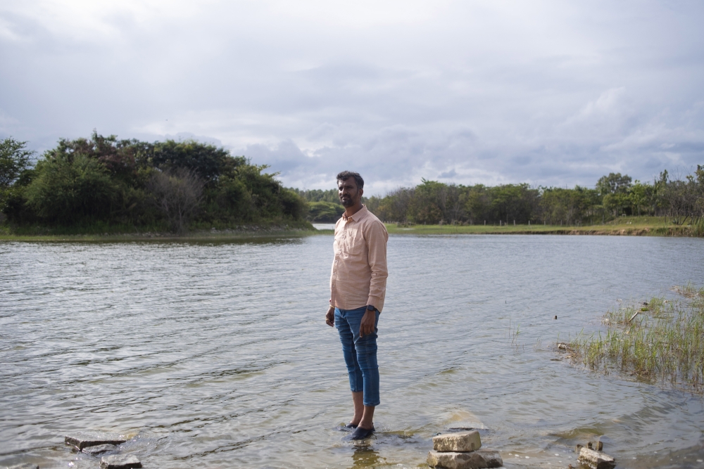 Anand Malligavad, a mechanical engineer known as “Lake Man,” stands in the clean waters of Kyalasanahalli Lake, his first reclamation project, in Bengaluru, India, July 28, 2023. (Priyadarshini Ravichandran/The New York Times)