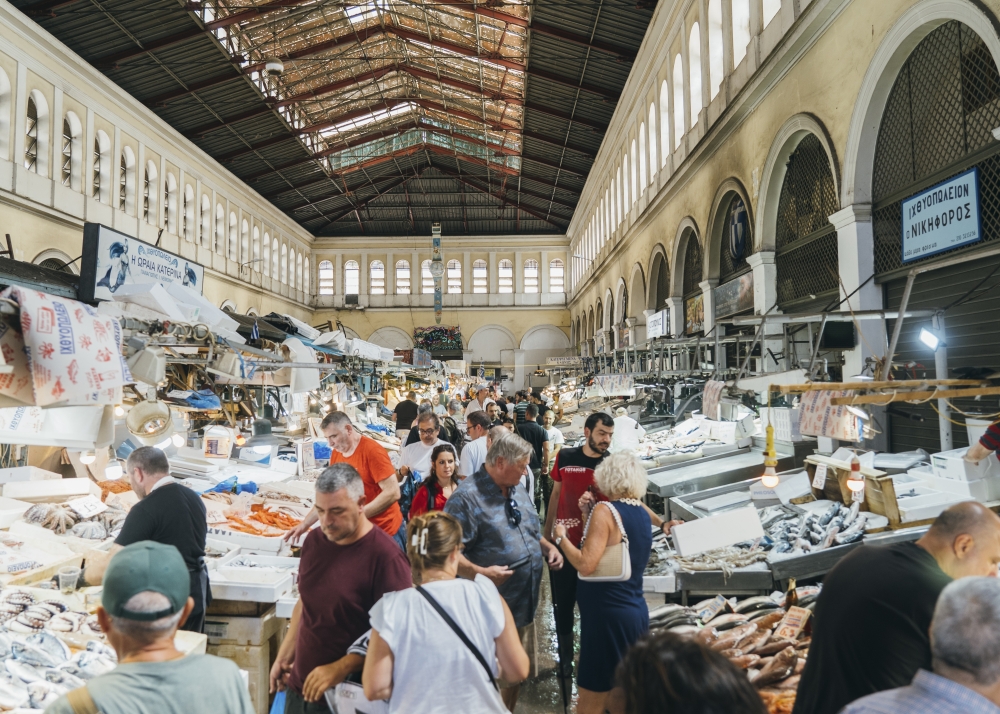Tourists and locals shop fish at the central market in Athens, on Sept. 9, 2023. (Marco Arguello/The New York Times)
