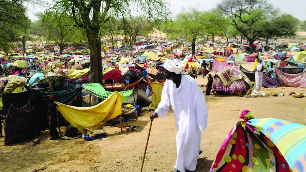 Sudanese men who fled the conflict in Sudan's Darfur region walks past makeshift shelters near the border between Sudan and Chad. — Reuters