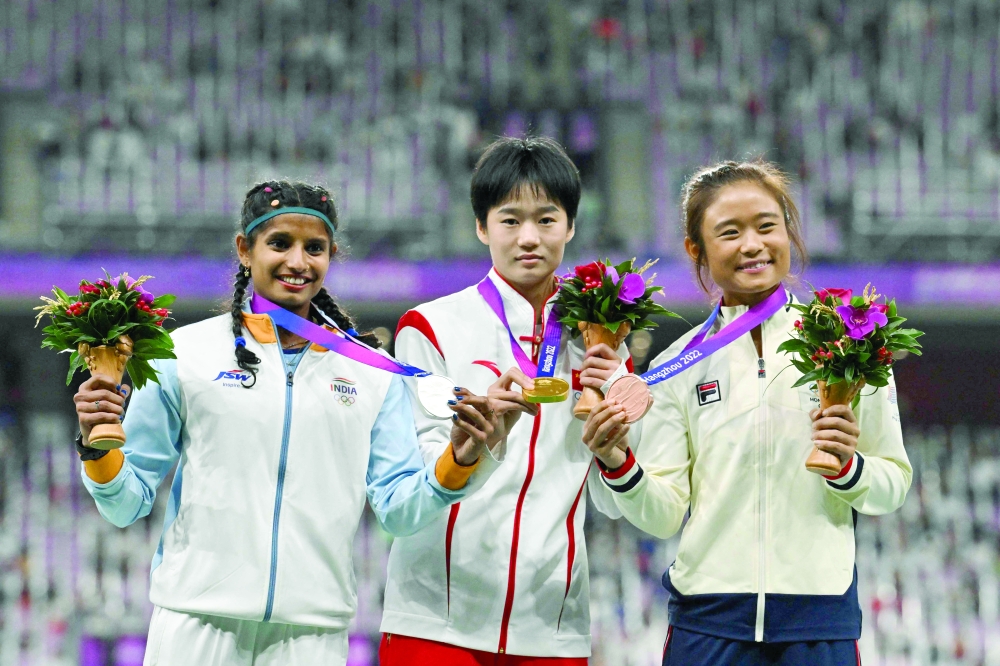 (L-R) Women's long jump silver medallist India's Ancy Sojan Edappilly, gold medallist China's Xiong Shiqi and bronze medallist Hong Kong's Yue Nga Yan celebrate on the podium. -- AFP