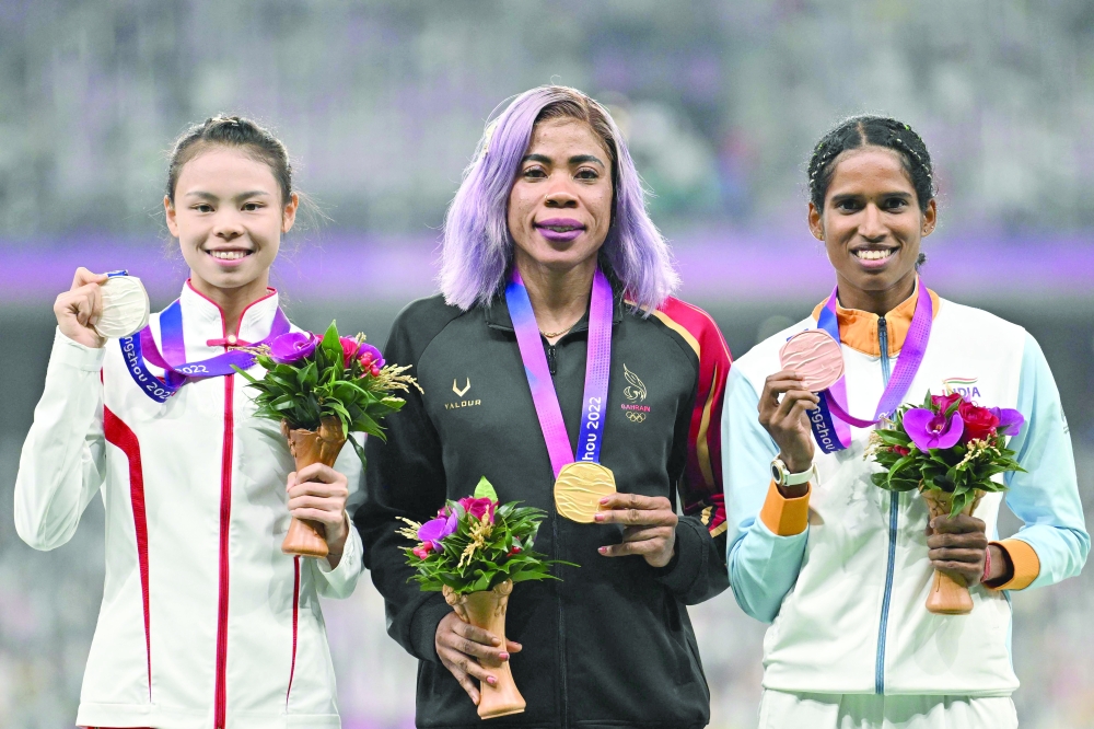 (L-R) Silver medallist China's Mo Jiadie, gold medallist Bahrain's Kemi Adekoya and bronze medallist India's Vithya Ramraj celebrate on the podium during the medal ceremony for the women's 400m hurdles final athletics event during the 2022 Asian Games in Hangzhou. —AFP