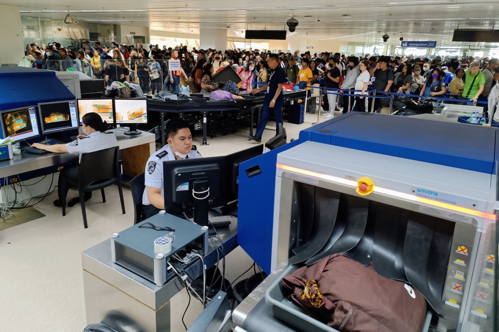 Departing travelers waiting in line for security checks as officials screen carry-on luggage at the Ninoy Aquino International Airport in metro Manila. 