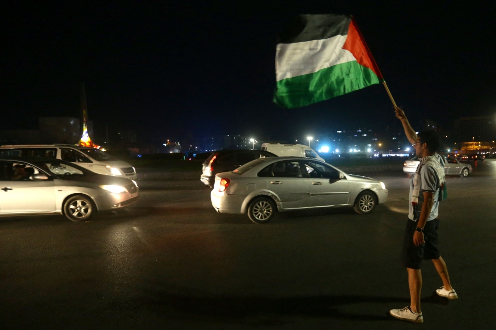 A man waves the Palestinian flag in Damascus on October 7, 2023, to express their solidarity with Palestine after Hamas militants launched a deadly air, land and sea assault into Israel from the Gaza Strip.  (Photo by LOUAI BESHARA / AFP)