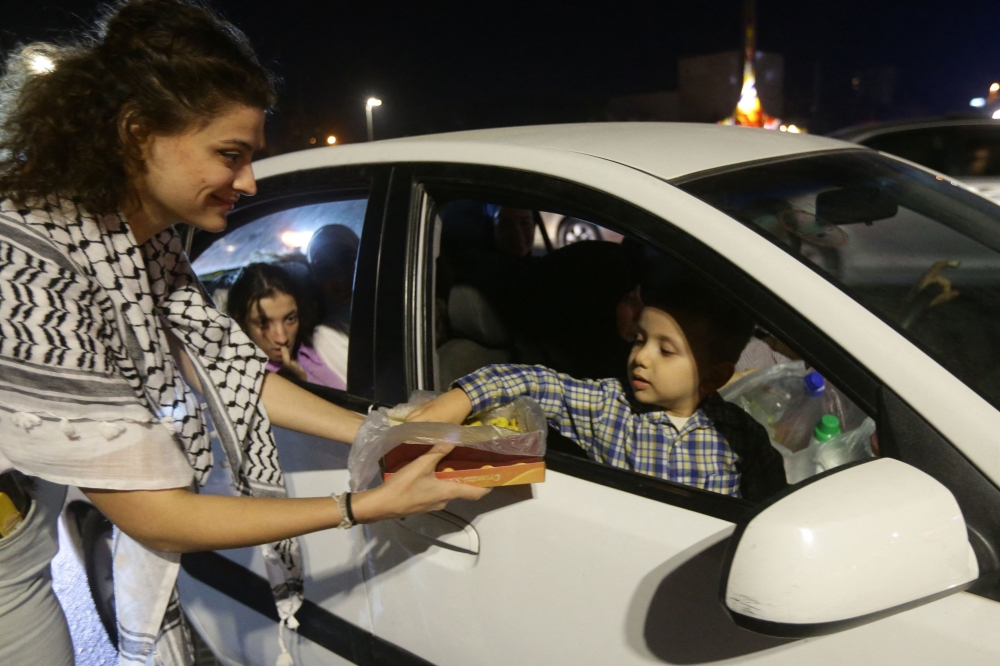 A girl passed out sweets to passers-by in Damascus on October 7, 2023, to express their solidarity with Palestine after Hamas militants launched a deadly air, land and sea assault into Israel from the Gaza Strip.  (Photo by LOUAI BESHARA / AFP)

