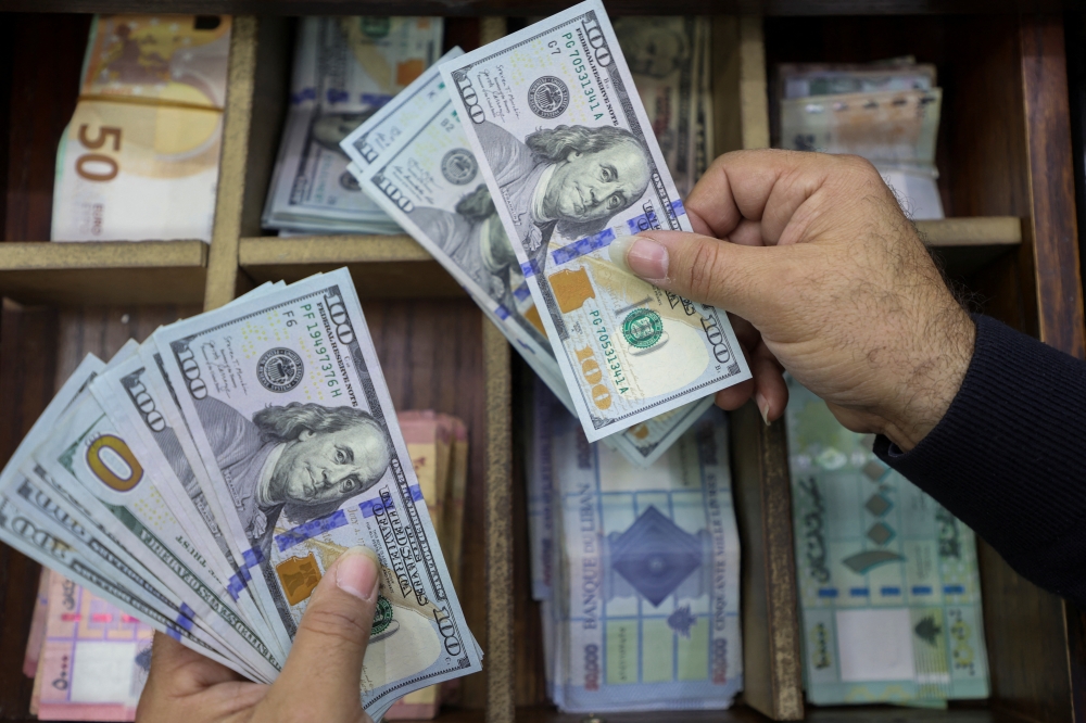 A money exchange vendor holds US dollar banknotes at his shop in Beirut, Lebanon. — Reuters