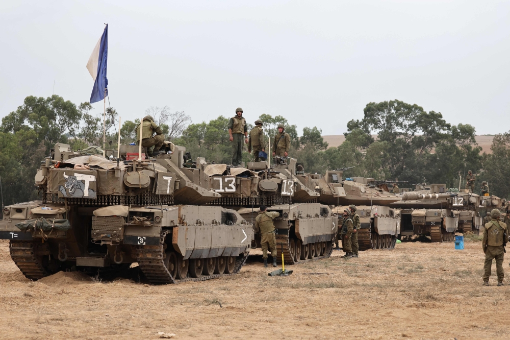 Israeli army soldiers are positioned with their Merkava tanks near the border with the Gaza Strip in southern Israel on October 9