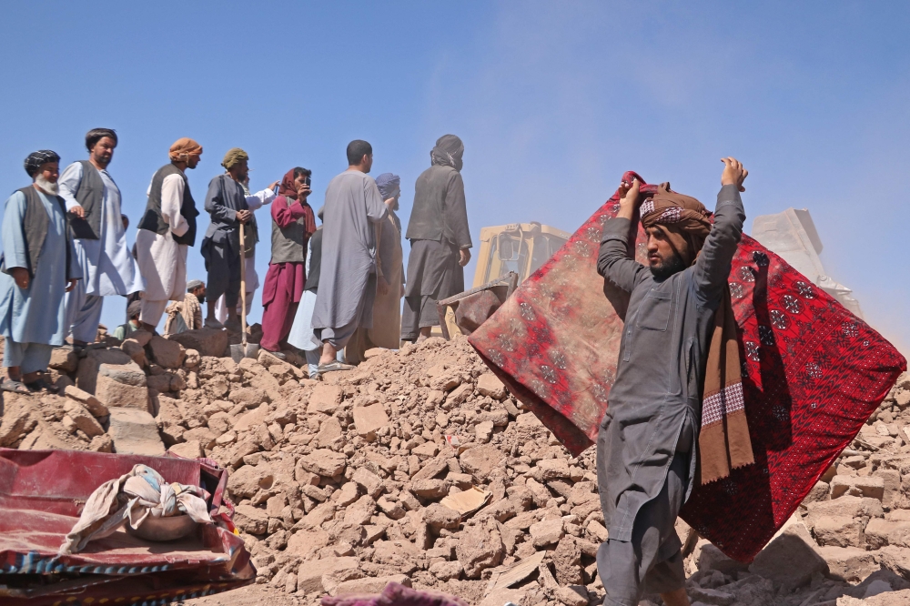 Afghan volunteers clear the debris of damaged village houses after a series of earthquakes in Zendeh Jan district