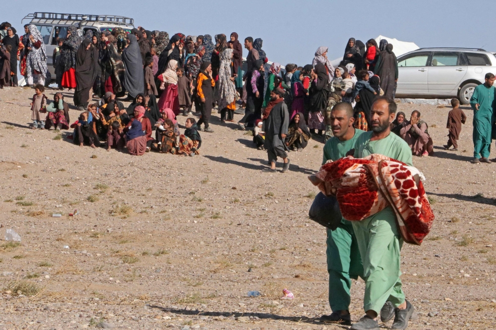 An Afghan man carries the dead body of a child during a mass funeral for the people killed in a series of earthquakes in Zendeh Jan district 