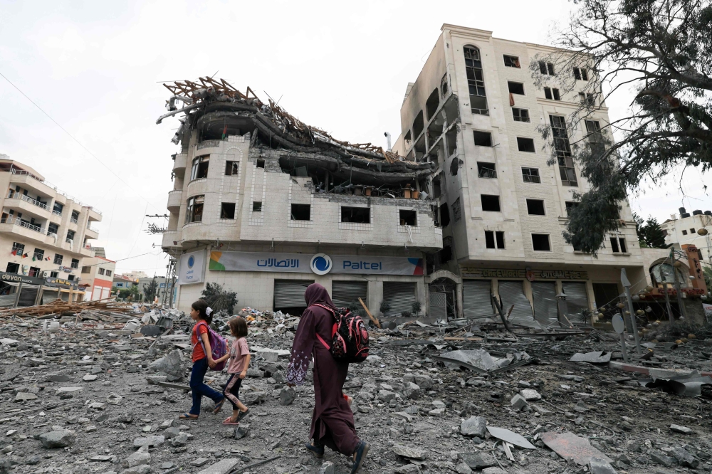 Palestinians walk through debris amid massive destruction from Israeli airstrikes in Gaza City's al-Rimal district