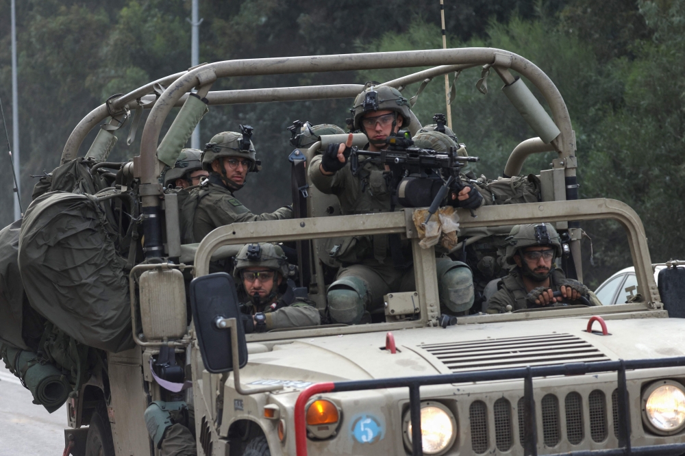 Israeli soldiers patrol a road near the border fence with Gaza on October 10, 2023.