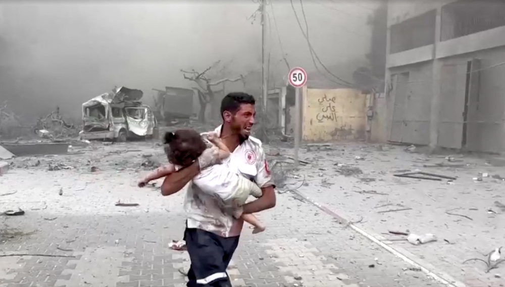 A medic runs as he carries an injured Palestinian child to ambulance