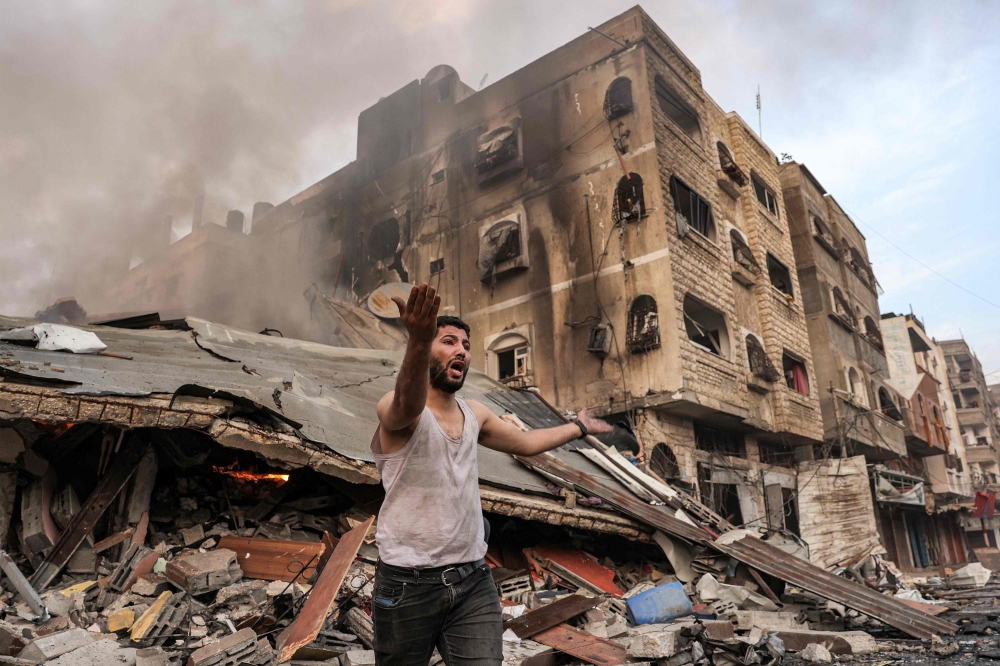 A man reacts outside a burning collapsed building following Israeli bombardment in Gaza City on October 11, 2023. 