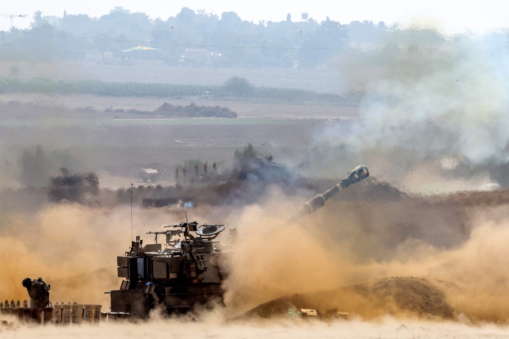 An Israeli army self-propelled howitzer fires rounds near the border with Gaza in southern Israel on October 11, 2023