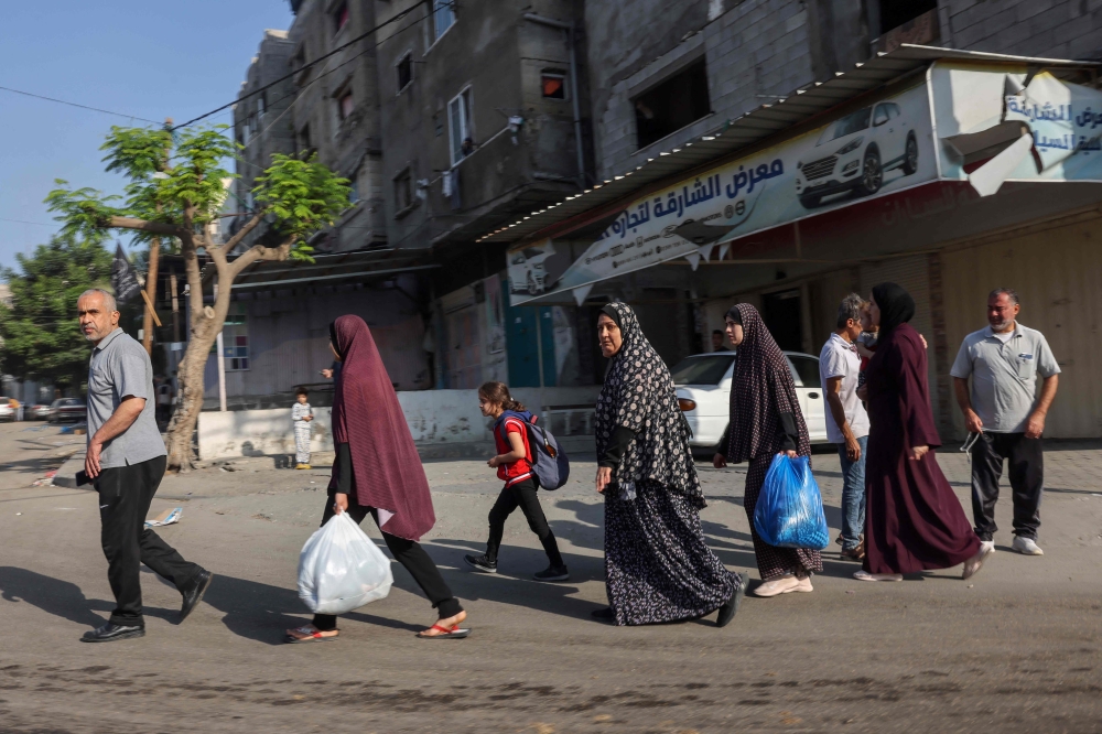 Palestinians carrying their belongings flee to safer areas in Gaza City after Israeli air strikes, 